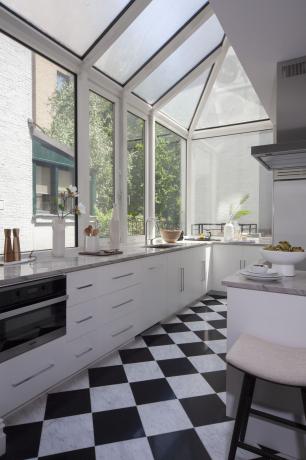 მზით ოთახში იატაკის ფილები მოთავსებულია სამზარეულოში თეთრი კაბინეტით და ბარის სკამებით