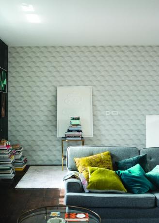 Papel de parede de fliperama na sala de estar branca com sofá de algodão cinza, almofadas coloridas e livros em exibição