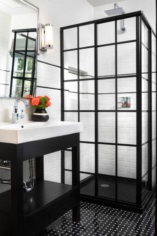 검은색 크리탈 도어가 있는 샤워 공간이 있는 흑백 욕실