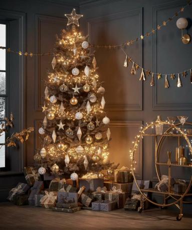 شجرة عيد الميلاد مضاءة بشكل مشرق وعربة بار في مساحة المعيشة مع ديكورات معلقة على الحائط