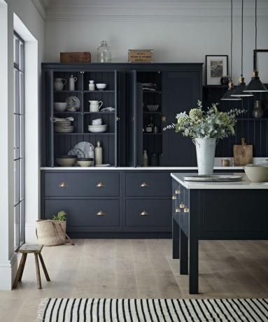 cucina blu scuro con piani di lavoro bianchi e tappeto a righe