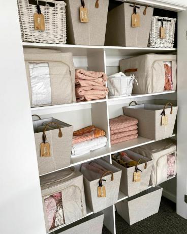 Un armario para ropa blanca con múltiples cajas de organización.