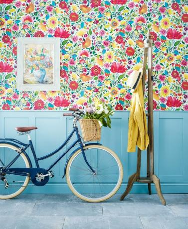 ziedu tapetes ar zilu apšuvumu, velosipēdu un mēteļu pakaramo