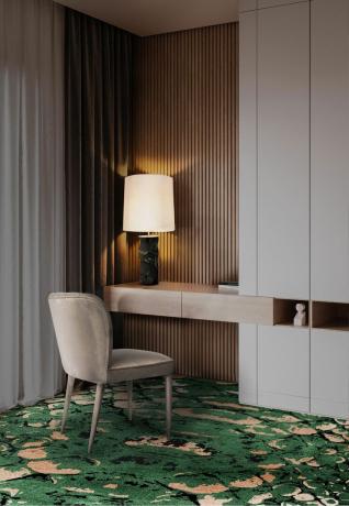 Moderni kotitoimisto, jossa on puiset seinät, vihreä kuvioitu abstrakti matto ja samettinen taupe -tuoli