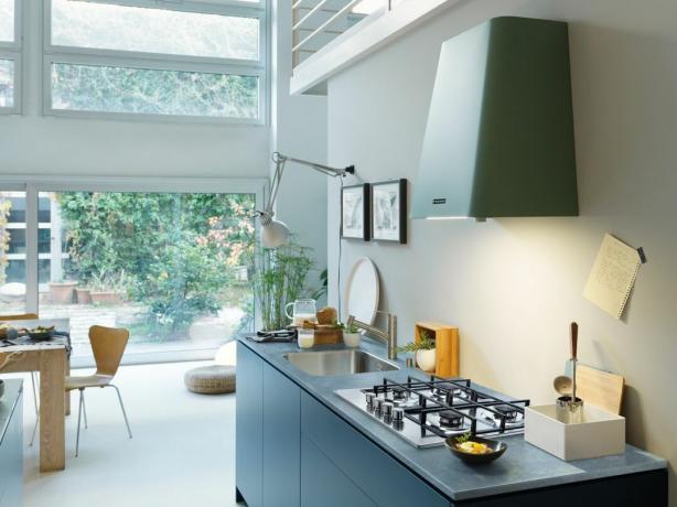 moderni atviro plano virtuvės valgomoji su žaliu gartraukiu ir mėlynomis spintelėmis be rankenų