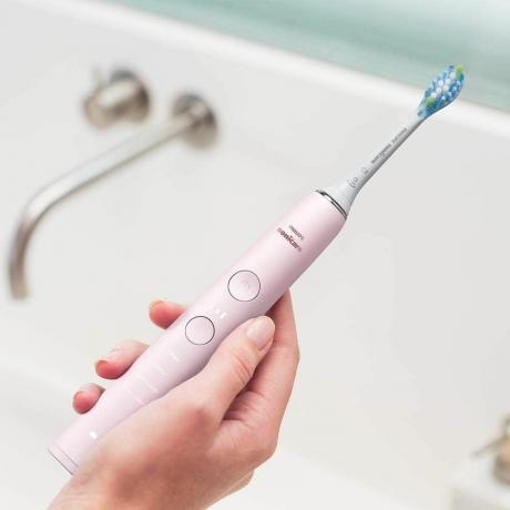 Revisão Philips Sonicare DiamondClean: escova de dentes elétrica rosa na mão sobre a pia