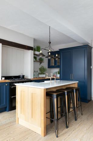 cozinha shaker azul escuro com ilha de madeira e bancos de bar de metal