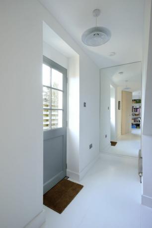 Pasillo con espejo y puerta trasera por Brown Architects