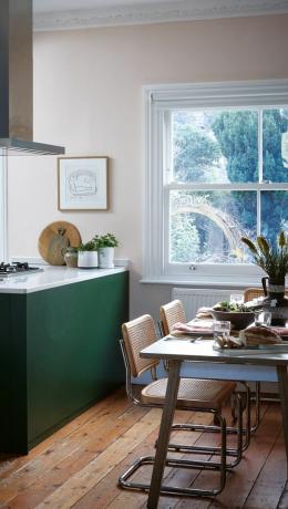 polotok v zeleni kuhinji z belimi marmornimi pulti, jedilna miza na enem koncu