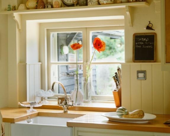 明るいキッチンの窓とポピーのある白いキッチン シンク