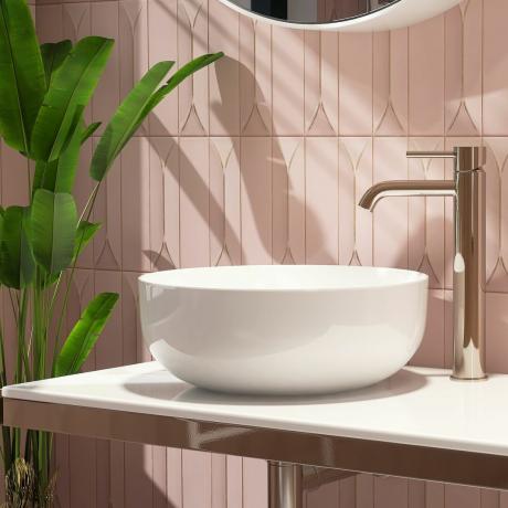 piastrelle del bagno rosa e un lavandino moderno bianco con una pianta vicina