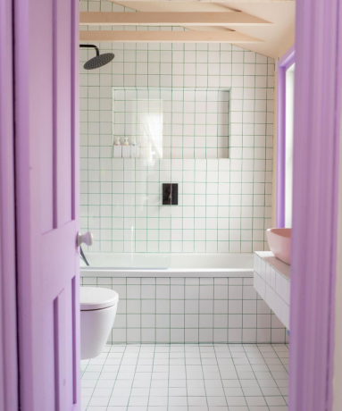 Svetlo bela kopalnica z lila poudarkom na vratih