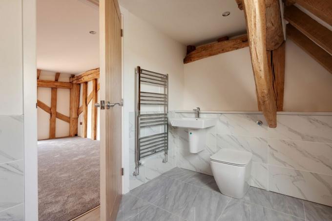 Toalheiro cromado em banheiro de fazenda com detalhes em madeira e piso neutro