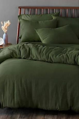 Yatakta Welhome yaşam tarzı görüntüsünden koyu yeşil nevresim takımı, saatli ve lambalı komodin