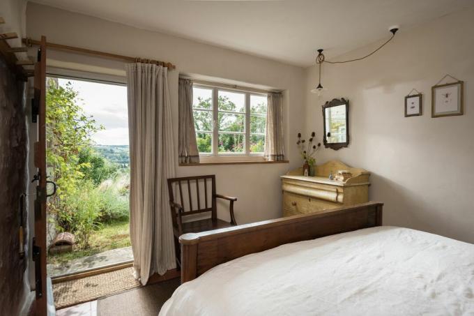 kamar tidur dengan pintu terbuka di pondok pedesaan yang telah direnovasi