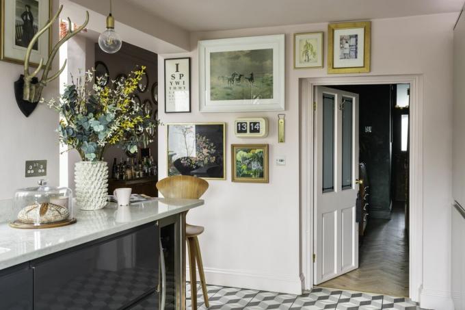 Virtuvės grindys turi 3D efekto rašto plyteles, kurios kontrastuoja su šviesiai rožinėmis sienų spalvomis