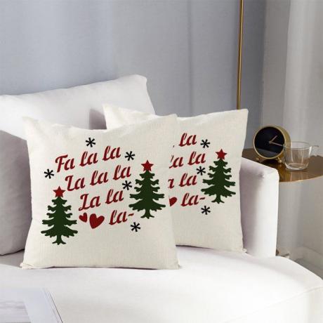 وسائد عيد الميلاد مكتوب عليها Fa la la la la على أريكة بيضاء في غرفة معيشة رمادية