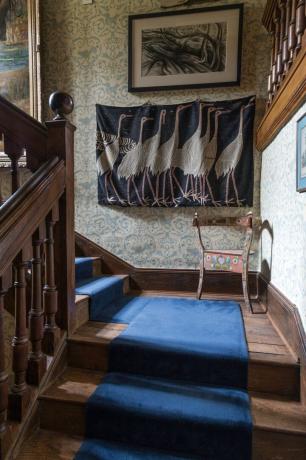 नीली सीढ़ी कालीन पुष्प वॉलपेपर लोक चित्रित कुर्सी के साथ जैकोबीन मनोर में सीढ़ी