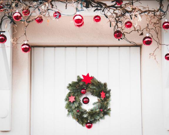 Jouluinen ulko-oven koristelu valkoinen ja punainen jouluseppeleellä