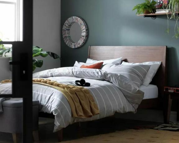 Rám manželskej postele Habitat Clanfield v spálni so sivými pruhovanými plachtami a modrou stenou