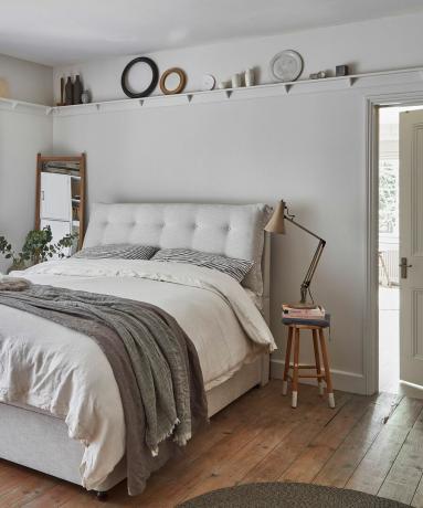 witte slaapkamer met wit dichtgeknoopt bed en lamp op bijzettafeltje