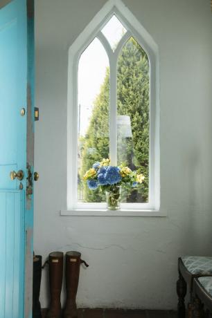 오래된 집을 에너지 효율을 높이는 방법: 독특한 창과 꽃이 있는 복도의 파란색 문