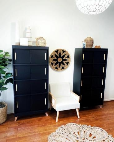 Dwa świeżo pomalowane czarne regały z drewnianym sprzętem ustawione w salonie z drewnianą podłogą i białymi ścianami