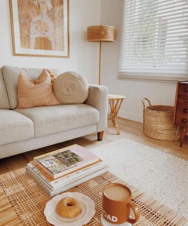 O cameră de zi bej și alb cu o canapea, măsuță de cafea și o lampă