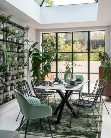 sala de jantar com portas estilo Crittal e parede de plantas
