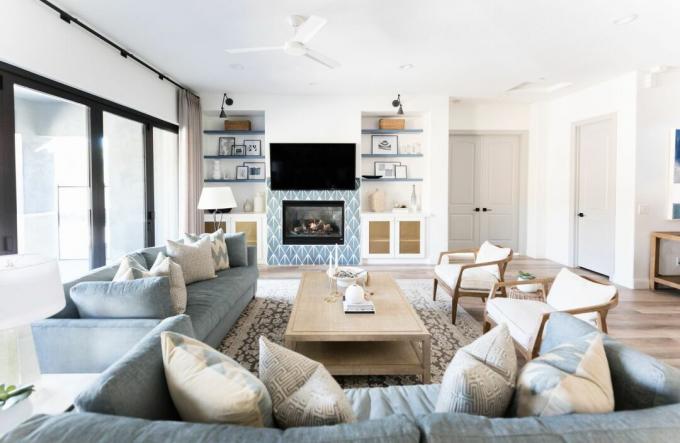 ruang tamu biru dan krem ​​dengan dinding putih, sofa biru, meja kopi kayu pucat