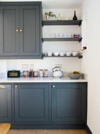 mørkeblå kjøkkenskap med benkeplater i marmorstil og utfyllingshyller