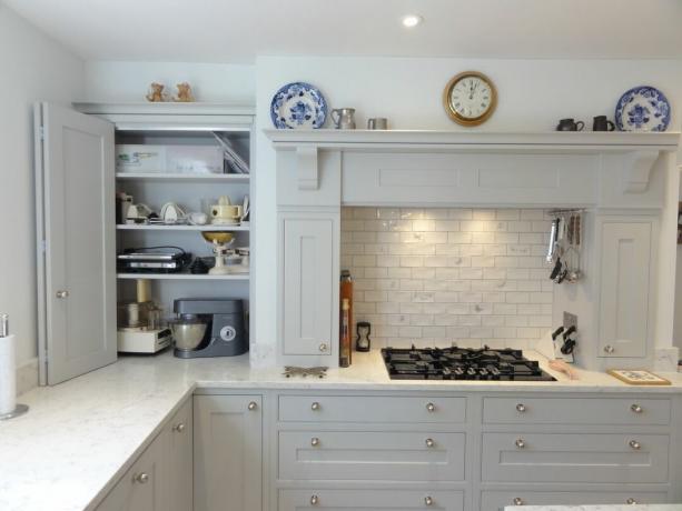 Witte tweevoudige keukenkastdeuren in witte ruimte met marmeren werkbladen en betegelde achterwand
