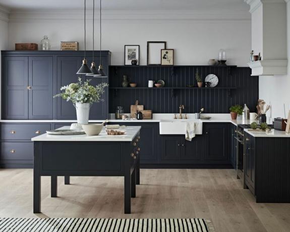 Schema cucina monocromatico con isola e armadi color carbone e piani di lavoro a contrasto in marmo e ferramenta in ottone brunito
