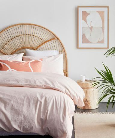 Helles Schlafzimmer mit Kopfteil aus Korbgeflecht und rosa Bettwäsche