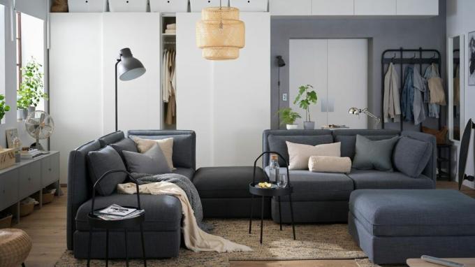 Une configuration de canapé modulaire gris dans un petit appartement avec un porte-manteau en arrière-plan