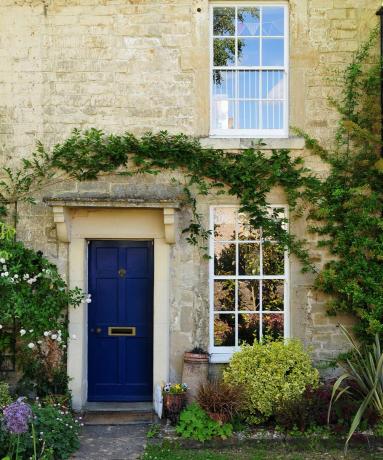Pondok batu dengan pintu biru dan ivy