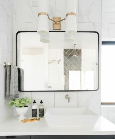Armário de banheiro cinza com pia branca, espelho de parede e iluminação de arandela branca