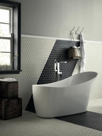 六角形の床と壁のタイル、白い浴槽と黒と白のバスルーム