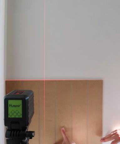 Claire Douglas folosește o nivelă laser Huapar pe perete pentru a realiza un proiect de lambriuri de perete