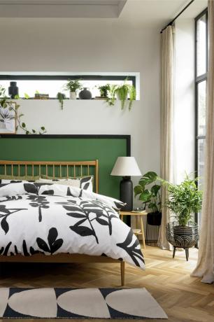 dormitor cu tăblie vopsită în verde, multe plante și așternut botanic monocrom