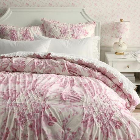 Lähikuva preppy-vaaleanpunaisesta sängystä ja yöpöydästä yövalolla keramiikkaladon asuntolassa