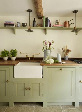 grønt kjøkken med benkeplater i tre og butlervask med kraner i messing