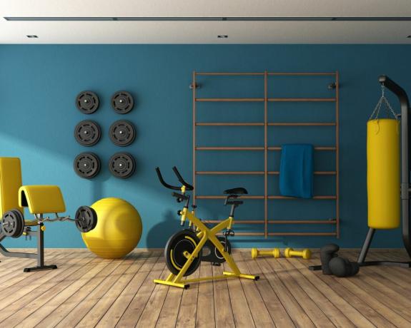 معدات رياضية صفراء في صالة رياضية منزلية في الطابق السفلي بالحائط الأزرق - جيتي