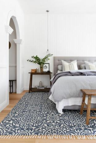 Weißes Schlafzimmer mit blau gemustertem Teppich