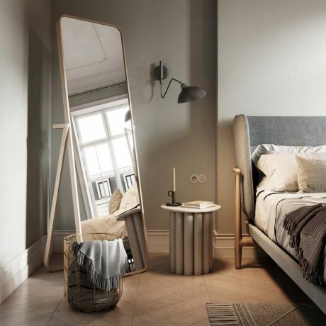 Scandi ložnice s zrcadlem po celé délce, velkou postelí s dřevěnými dlaždicemi a nočním stolkem s nástěnným svícnem