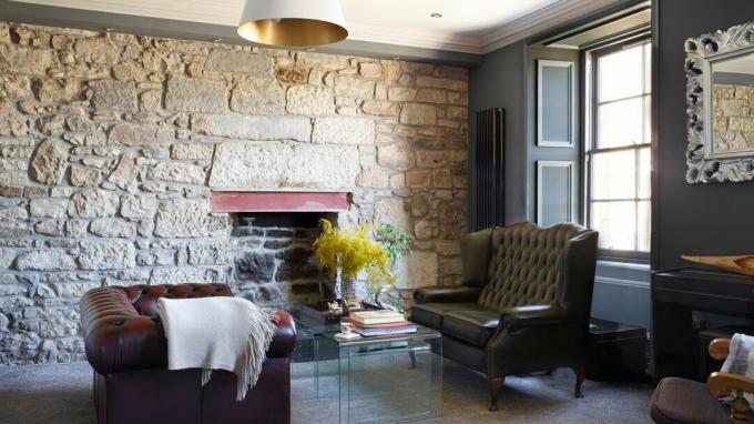 Sedie Chesterfield in un soggiorno con parete in pietra a vista
