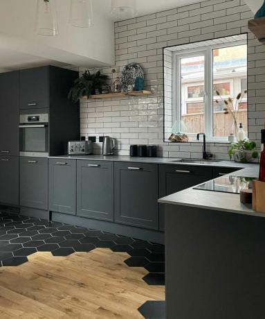 Una cocina gris oscuro recientemente renovada con suelo de madera parcialmente embaldosado con baldosas negras hexagonales