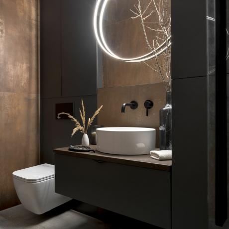 temna rustikalna in sodobna kopalnica z umivalnikom in straniščem ter minimalno osvetlitvijo