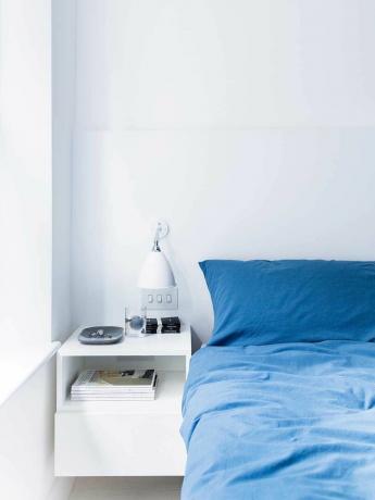 londýnsky byt biela spálňa modrá posteľná bielizeň nočný stolík
