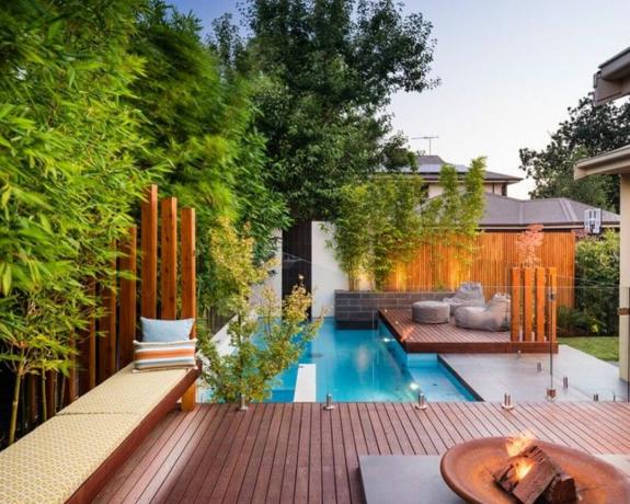 O zonă de terasă la piscină din lemn cald, cu zonă de relaxare suplimentară